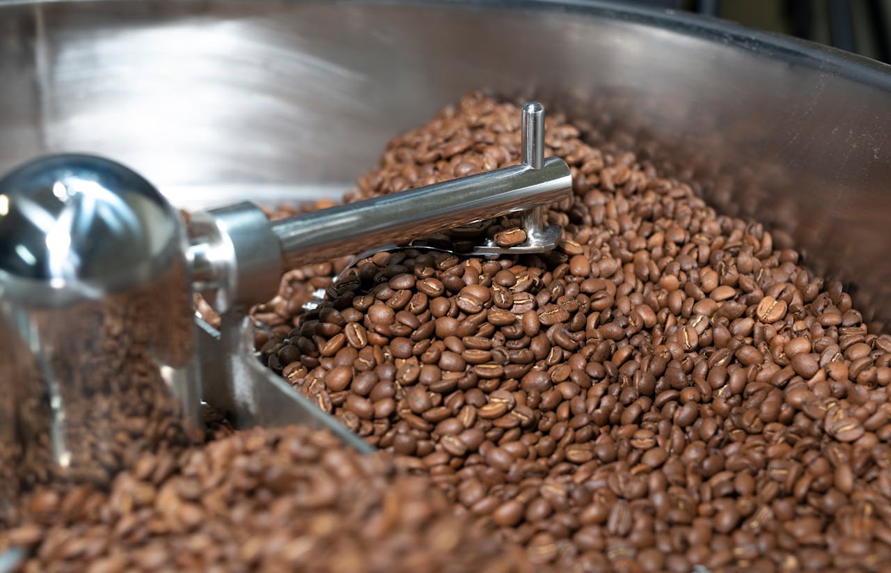 Freshly roasted coffee beans cooling in a metal drum, showcasing an industrial process.