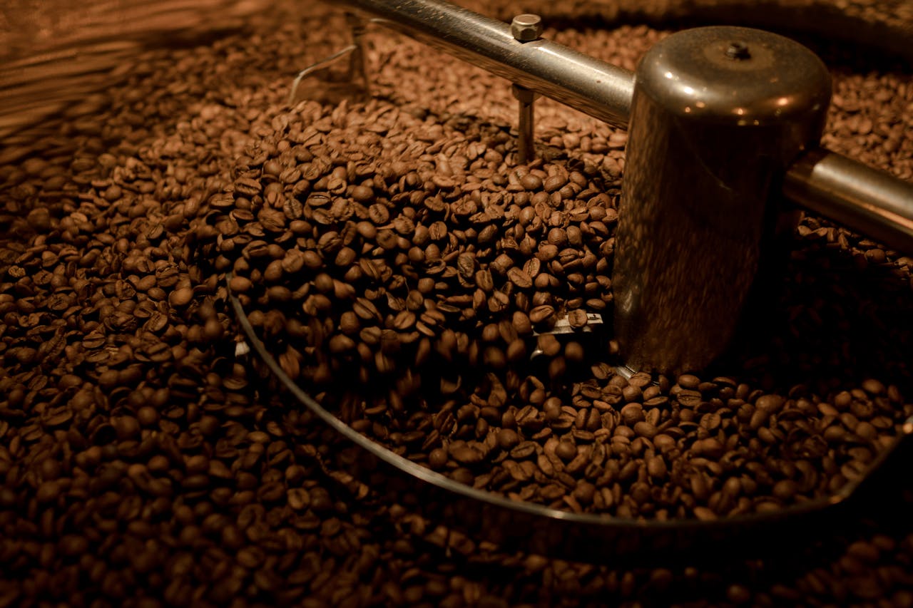 Detailed view of coffee beans being roasted in an industrial roaster. Perfect for coffee enthusiasts.
